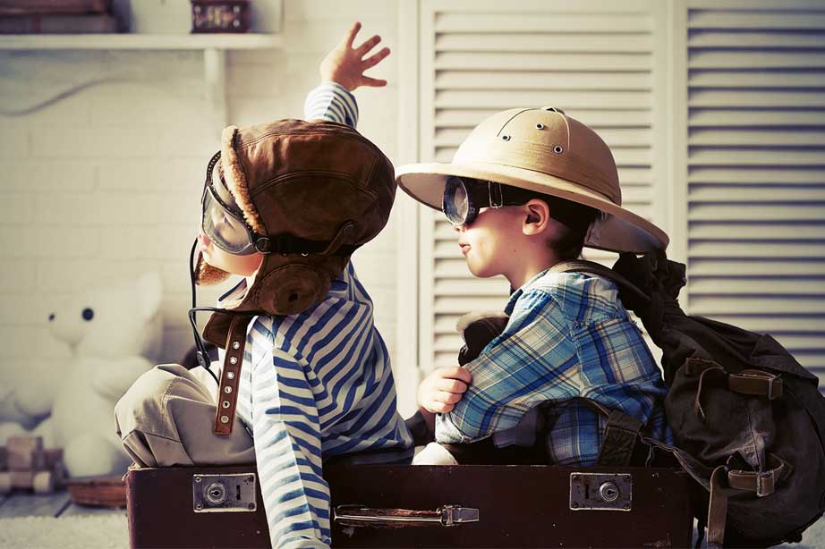 two kids playing in suitcase in bedroom