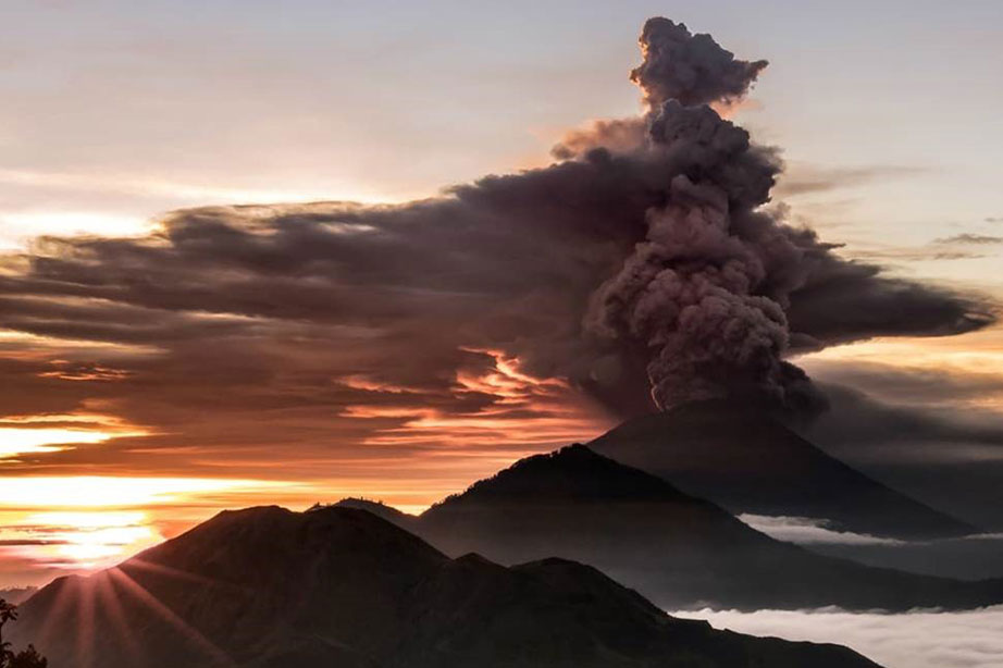 ash cloud over volcano during sunset