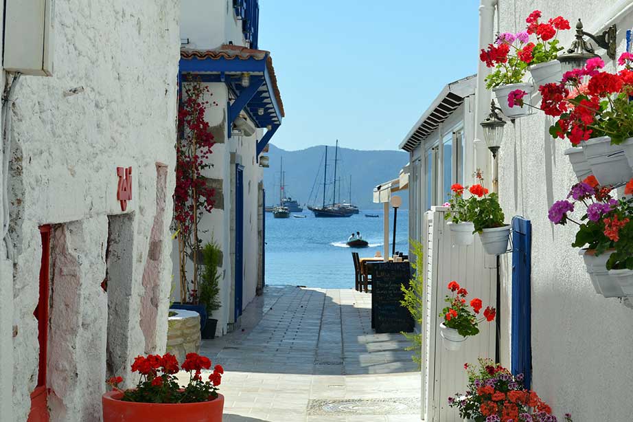 alley with houses and flowers overlooking harbour of bodrum with boats