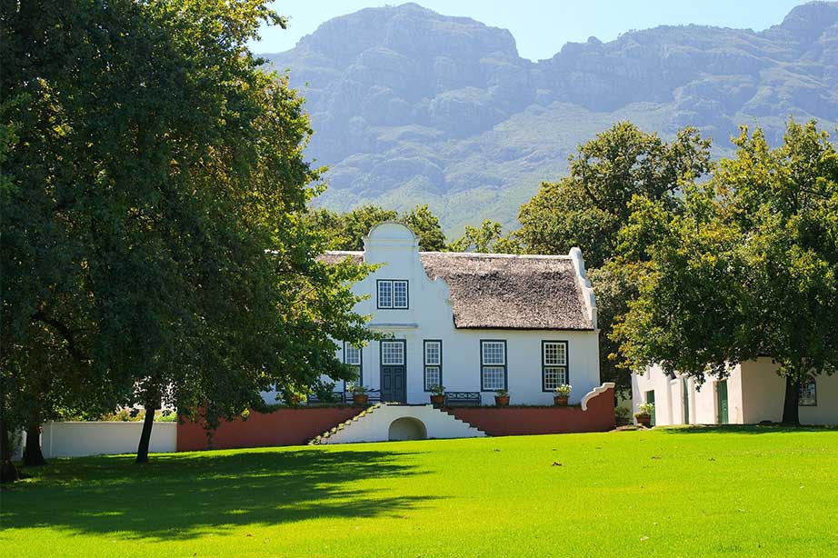 wine farm on stellenbosch in south africa with grassfield and trees surrounded by mountains