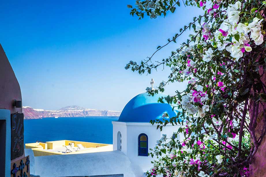 blue sky and sea in greece by a white chapel and tree