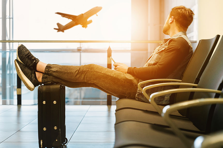 man with trolley case at airport watching plane taking off