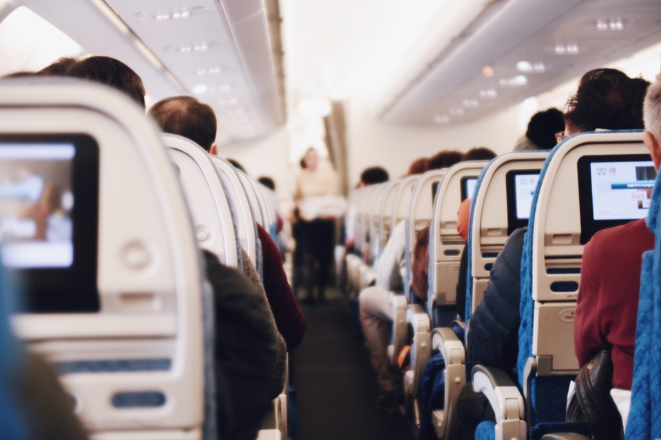 People sitting inside the airplane playing with the seatback touch screens