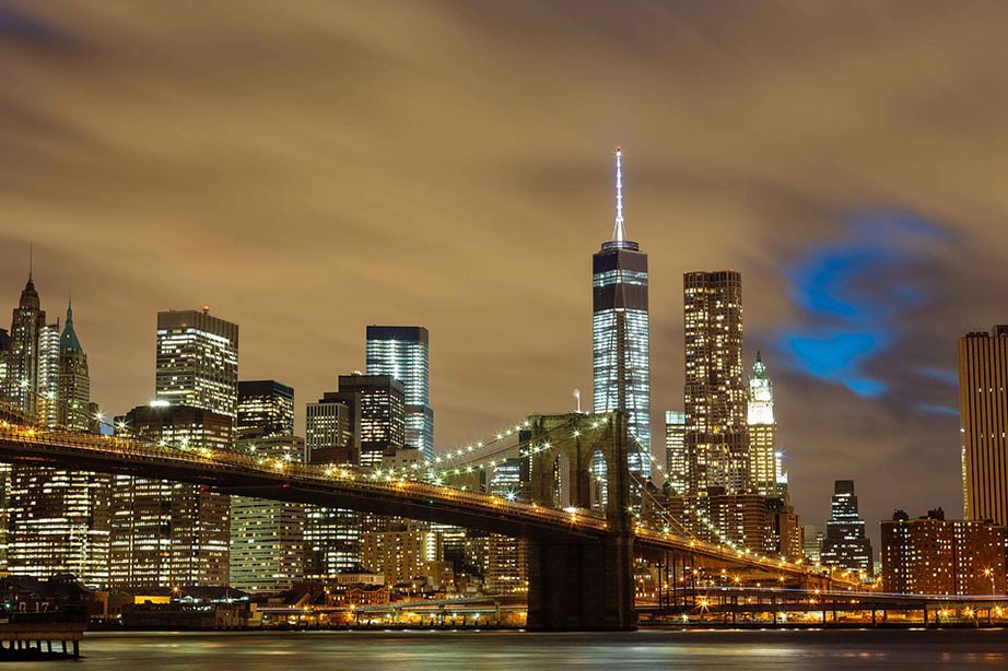 Brooklyn Bridge lighted at night with view over the New York Skyline