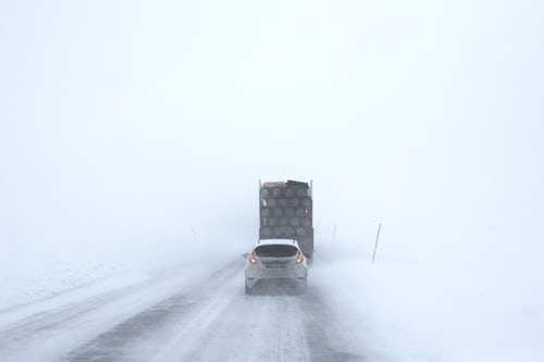 white car behind a truck on snowy road