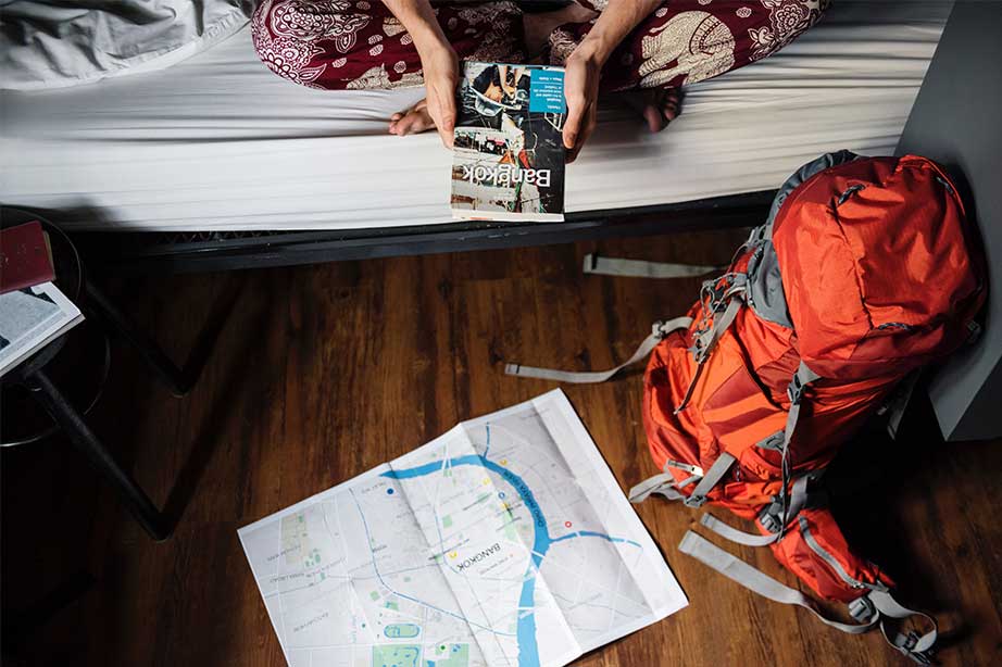 girl on bed planning her trip with a map of bangkok