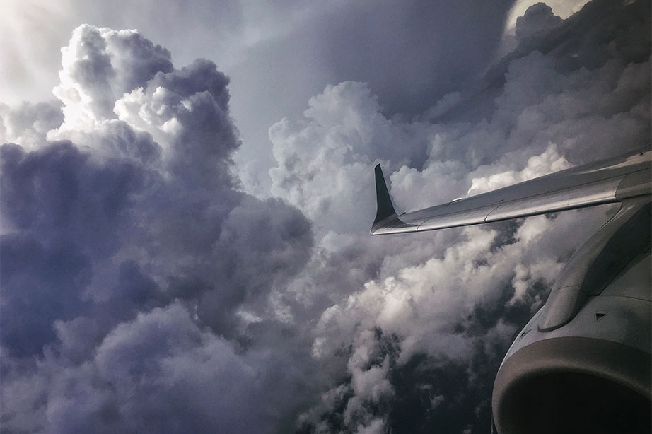 wing of plane in clouds and dark sky