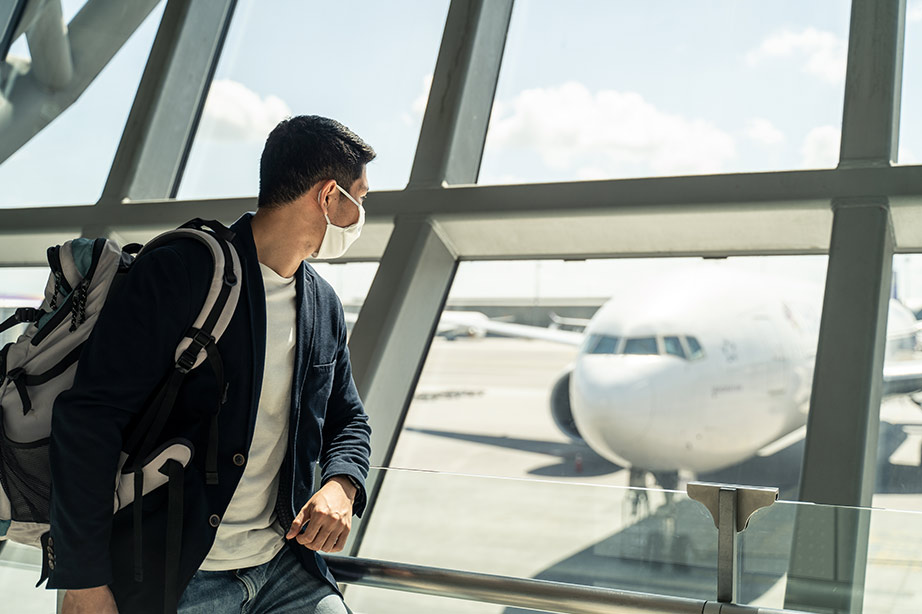 passenger with facemask looking at airplane