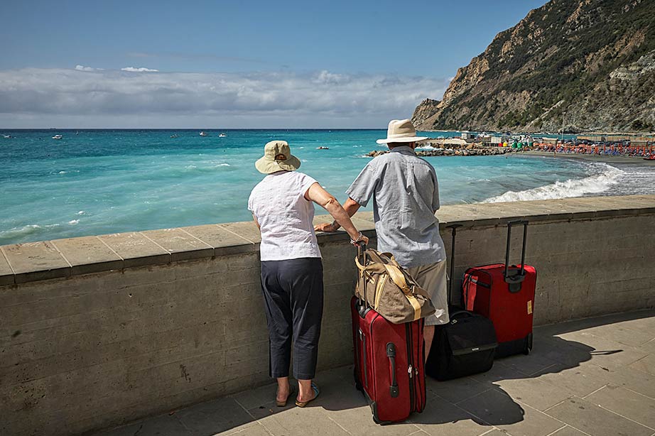 Couple standing in front of the beach with their suitcases