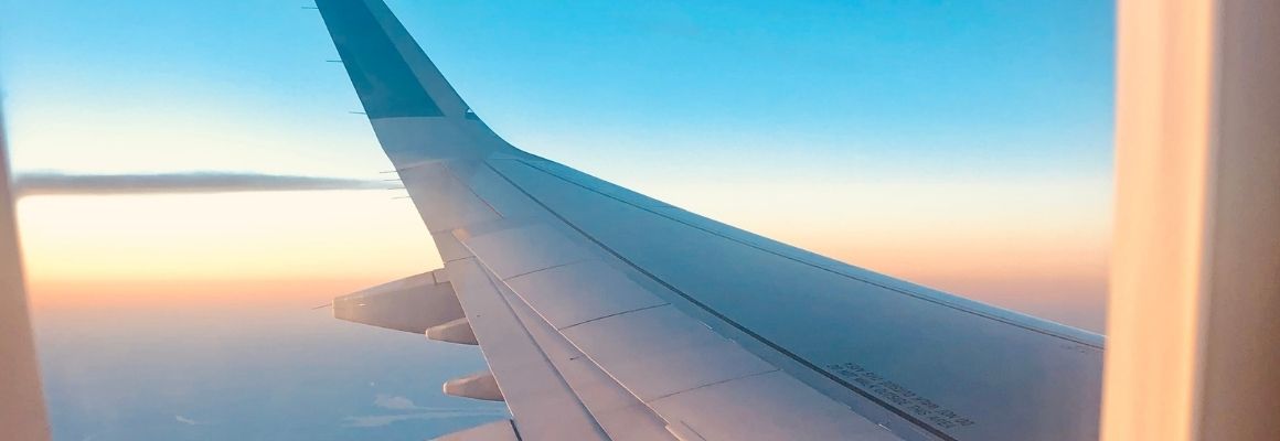 Airplane wing seen from a window during sunset above the clouds.
