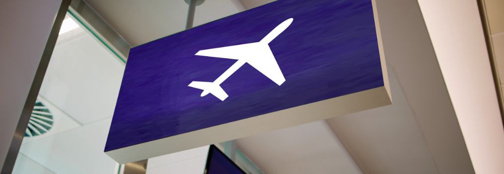 Airport sign with a white airplane icon indicating the direction of flight departures.